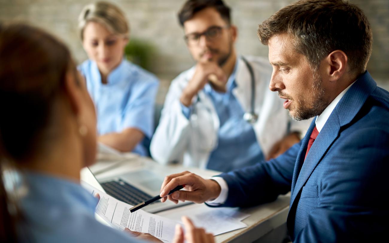 mid-adult-businessman-healthcare-workers-analyzing-documents-meeting-office.jpg