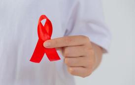 young-woman-s-hand-holding-red-aids-awareness-ribbon